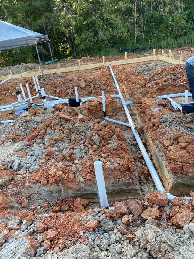 White plumbing lines installed in red soil for a new construction project