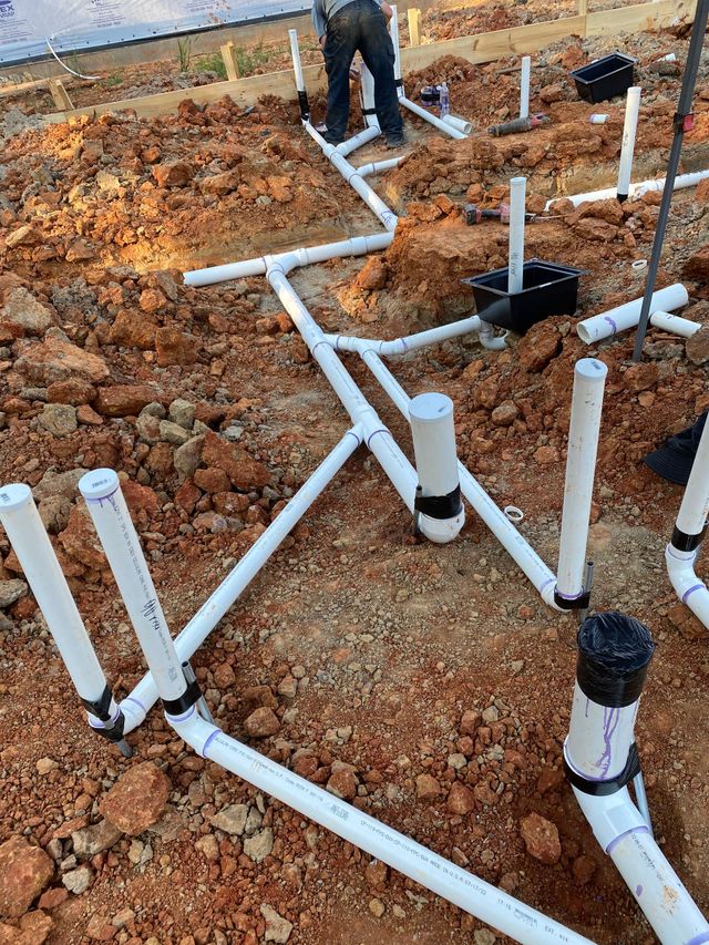 Plumber installing white drainage pipe in a construction area