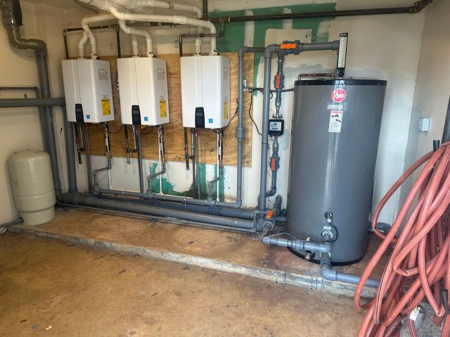 Three water heaters connected in a utility room